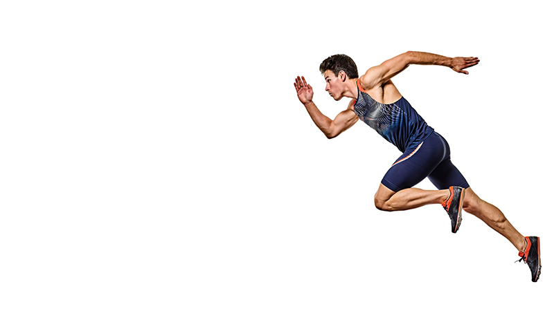 A male athlete in a blue sports outfit sprints forward against a plain white background.