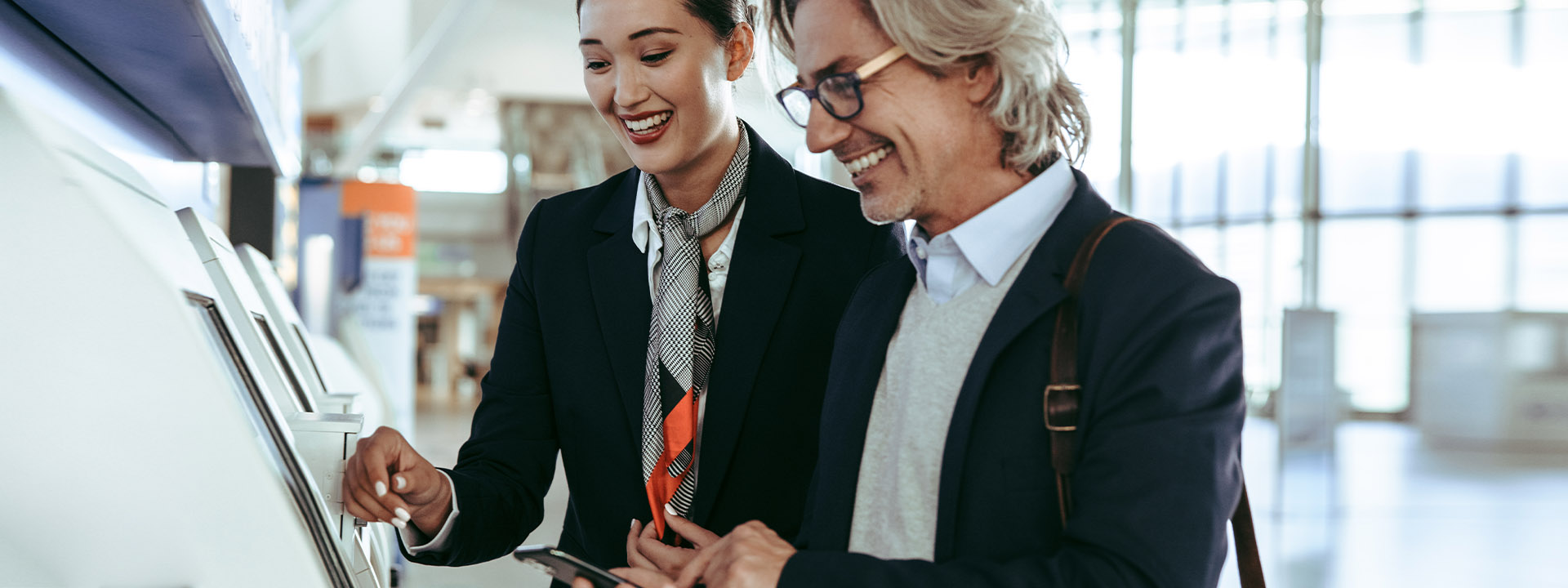 A man and woman in business attire examining a machine, possibly discussing its functionality and features.