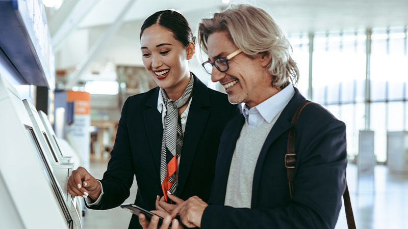 A man and woman in business attire examining a machine, possibly discussing its functionality and features.